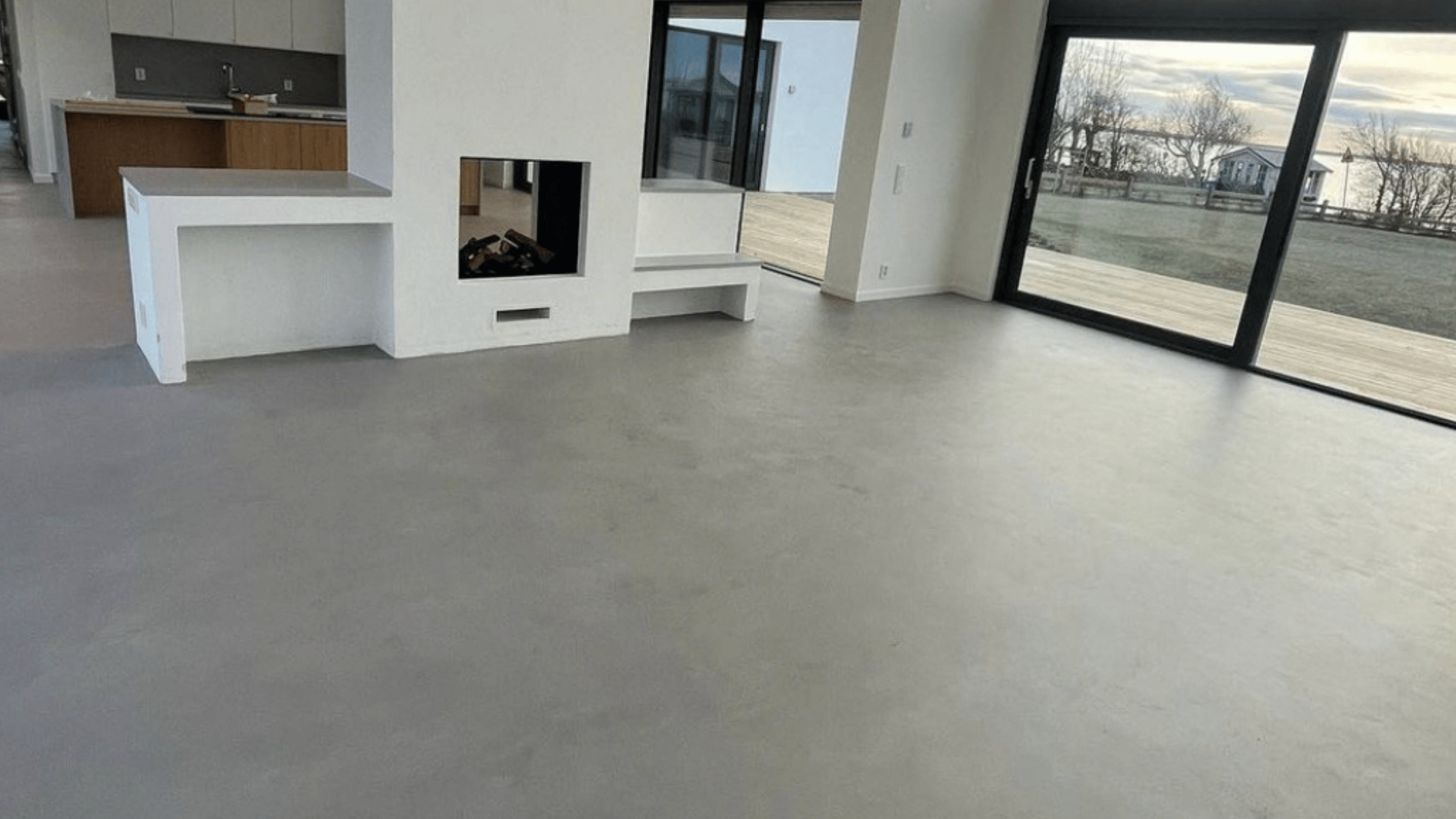 Ett rum med öppen planlösning och ett tilltalande ljusgrått microcementgolv.