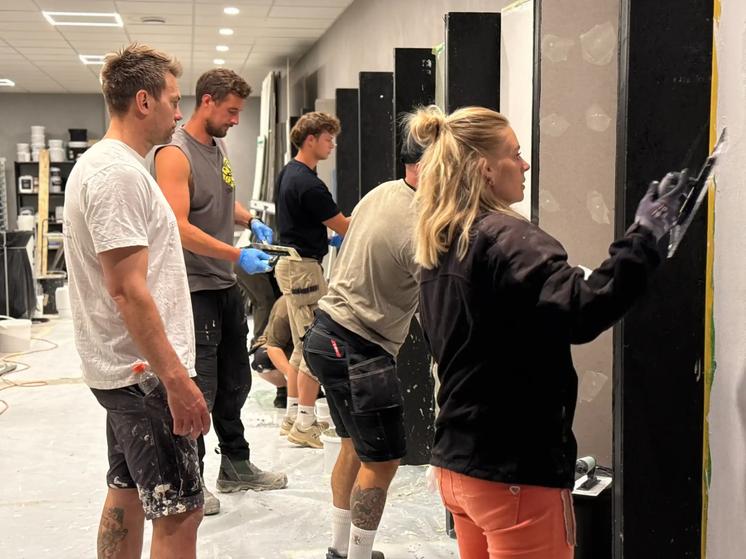 Kursdeltagare som lär sig lägga microcement på vägg under en yrkesutbildning i microcement